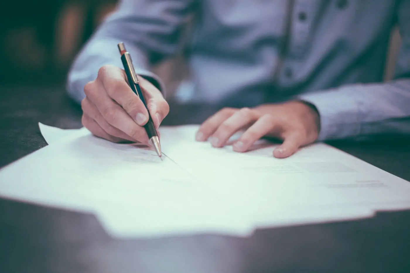 Persona firmando un documento con pluma